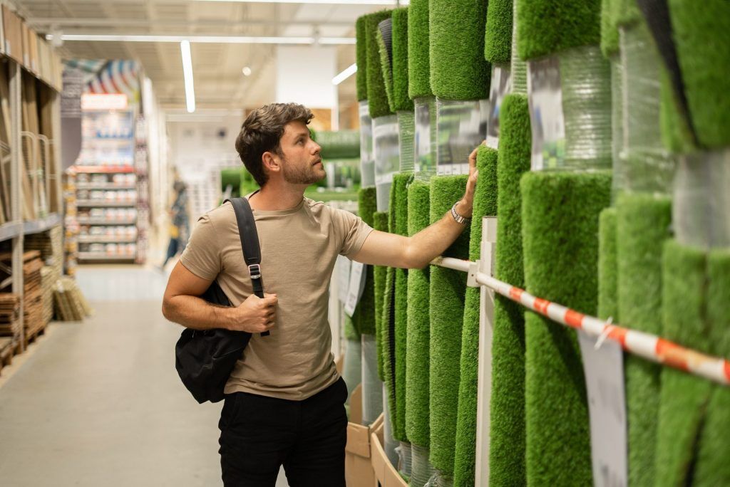 man looking at artificial turf in a store